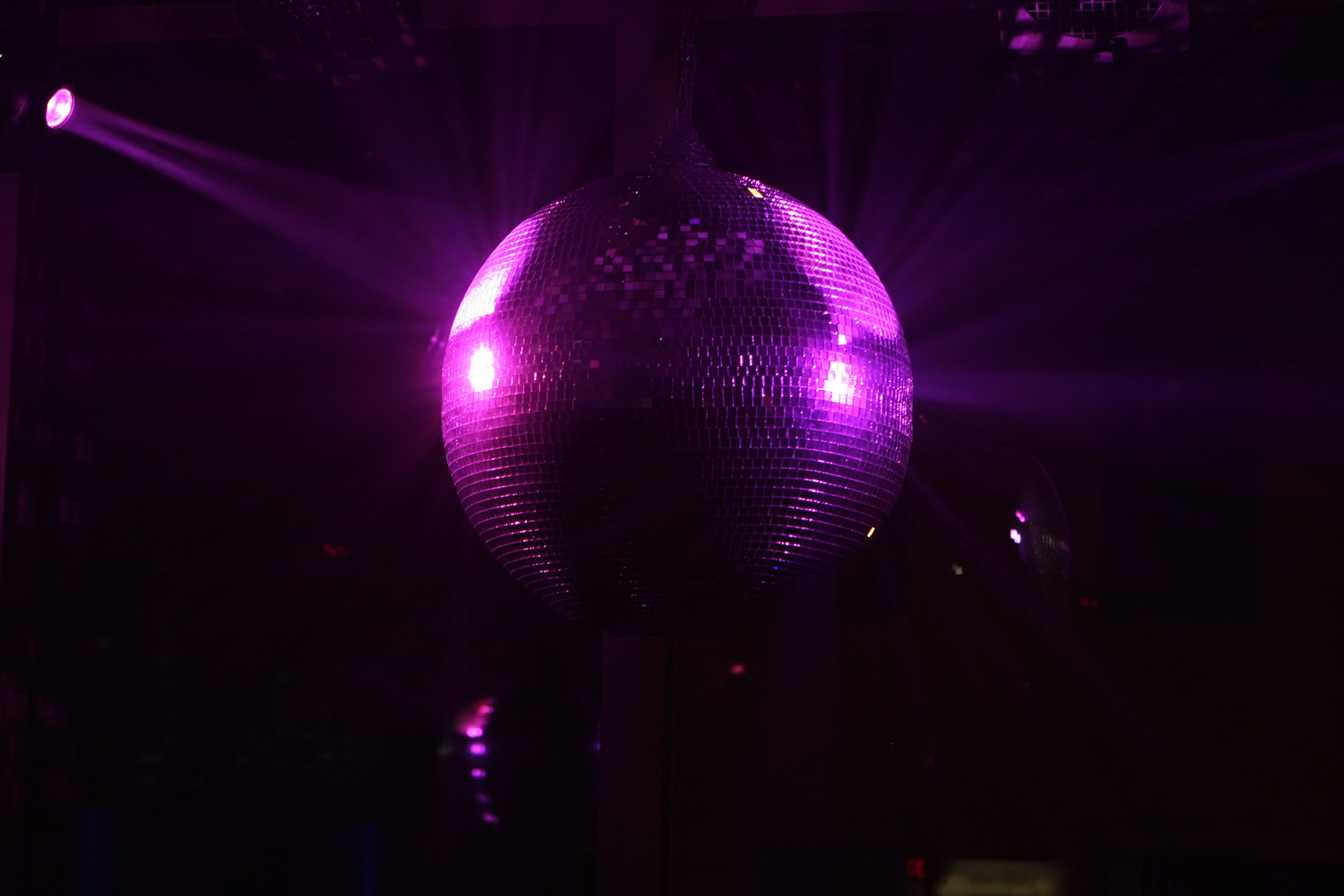 Discoball reflecting violet light beams in dark disco ambiente